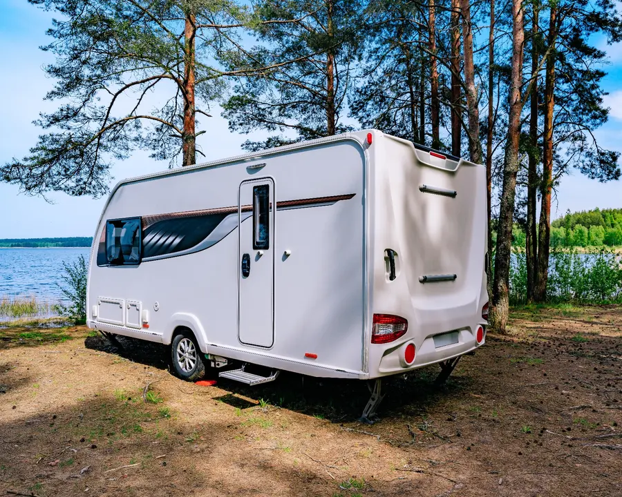 White caravan parked beside a tranquil lake